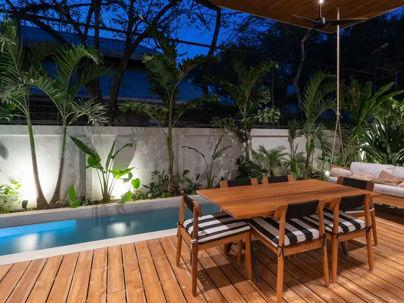 Teak deck and outdoor dining set under string-lit trees at night