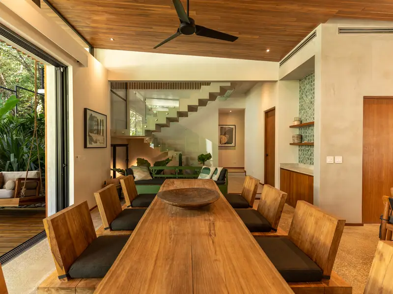 Twelve-seat teak dining table beneath the floating staircase