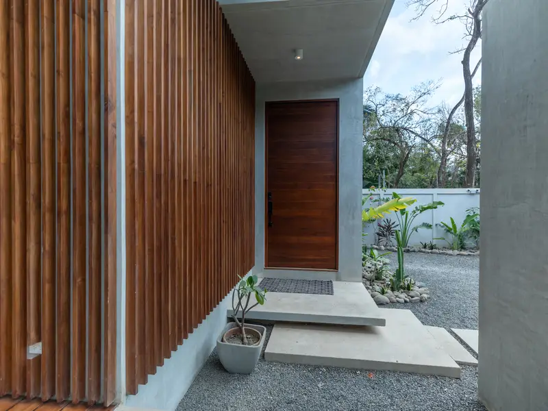 Solid teak front door behind a screen of slatted hardwood