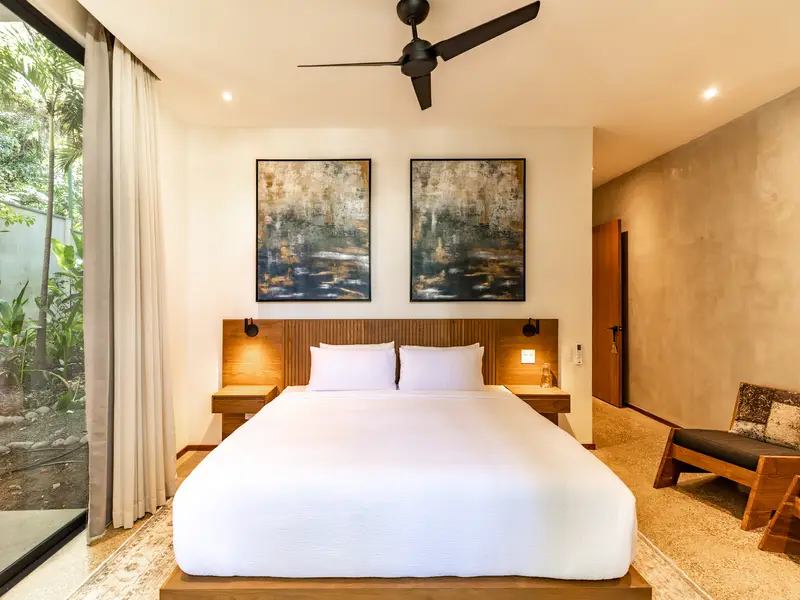King bedroom with oversized abstract art and jungle-view glass wall