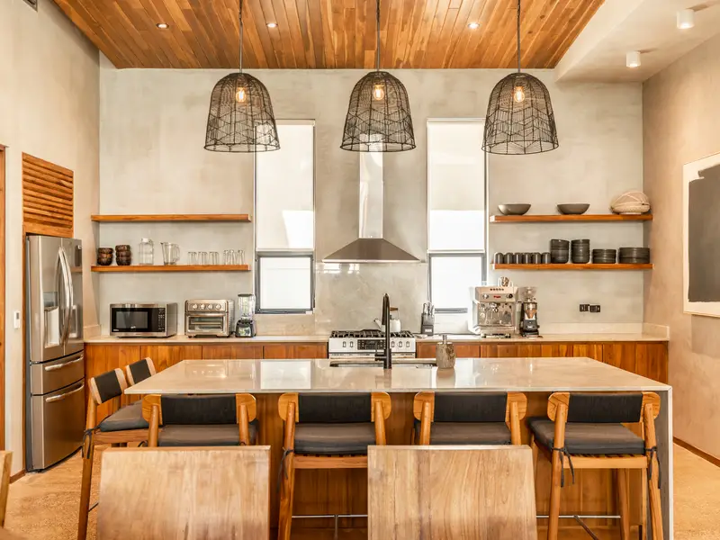 Kitchen island under woven pendant lights with full range and hood