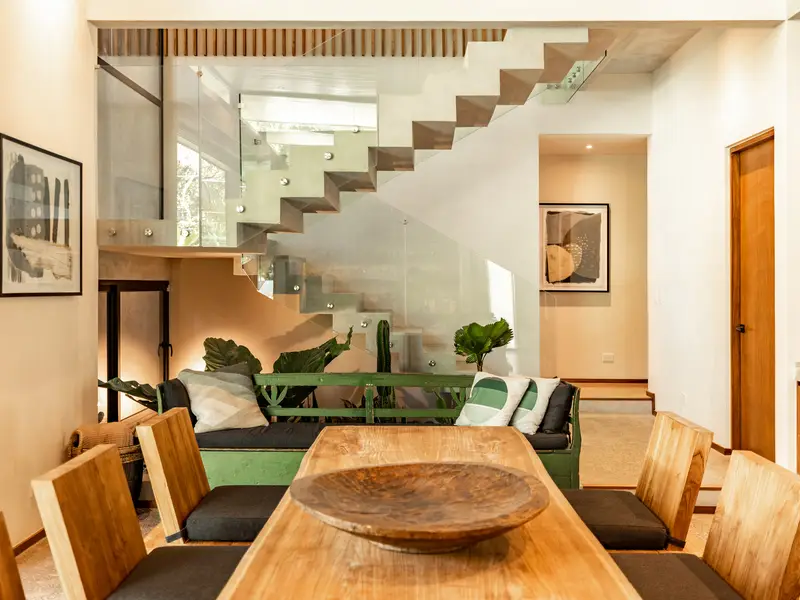 Sunken lounge with green sofa at the base of the staircase
