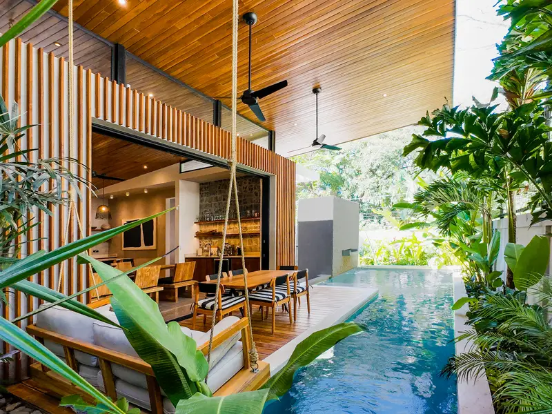 Saltwater pool along the villa's slatted teak facade, framed by jungle