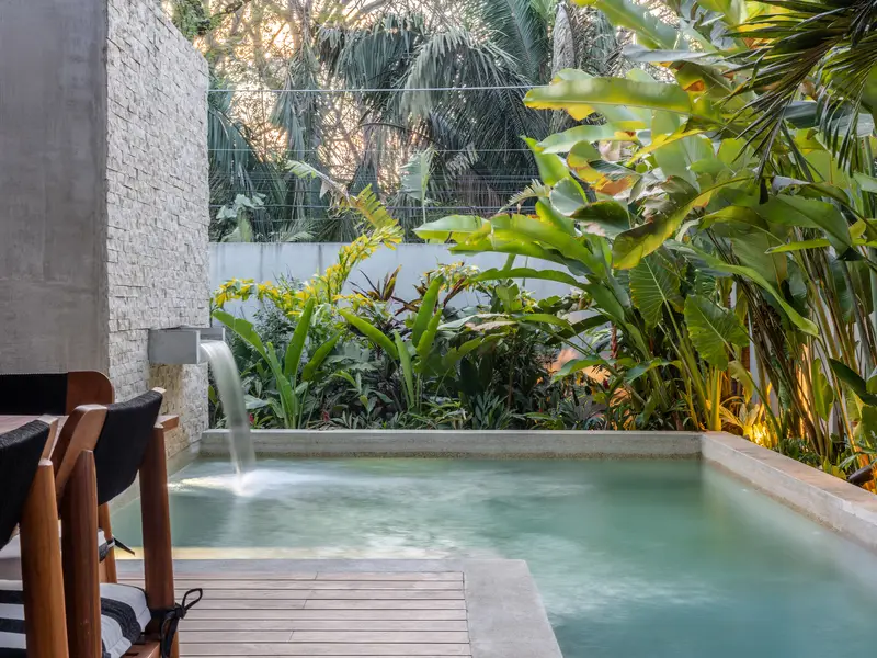 Pool waterfall surrounded by banana palms and heliconia