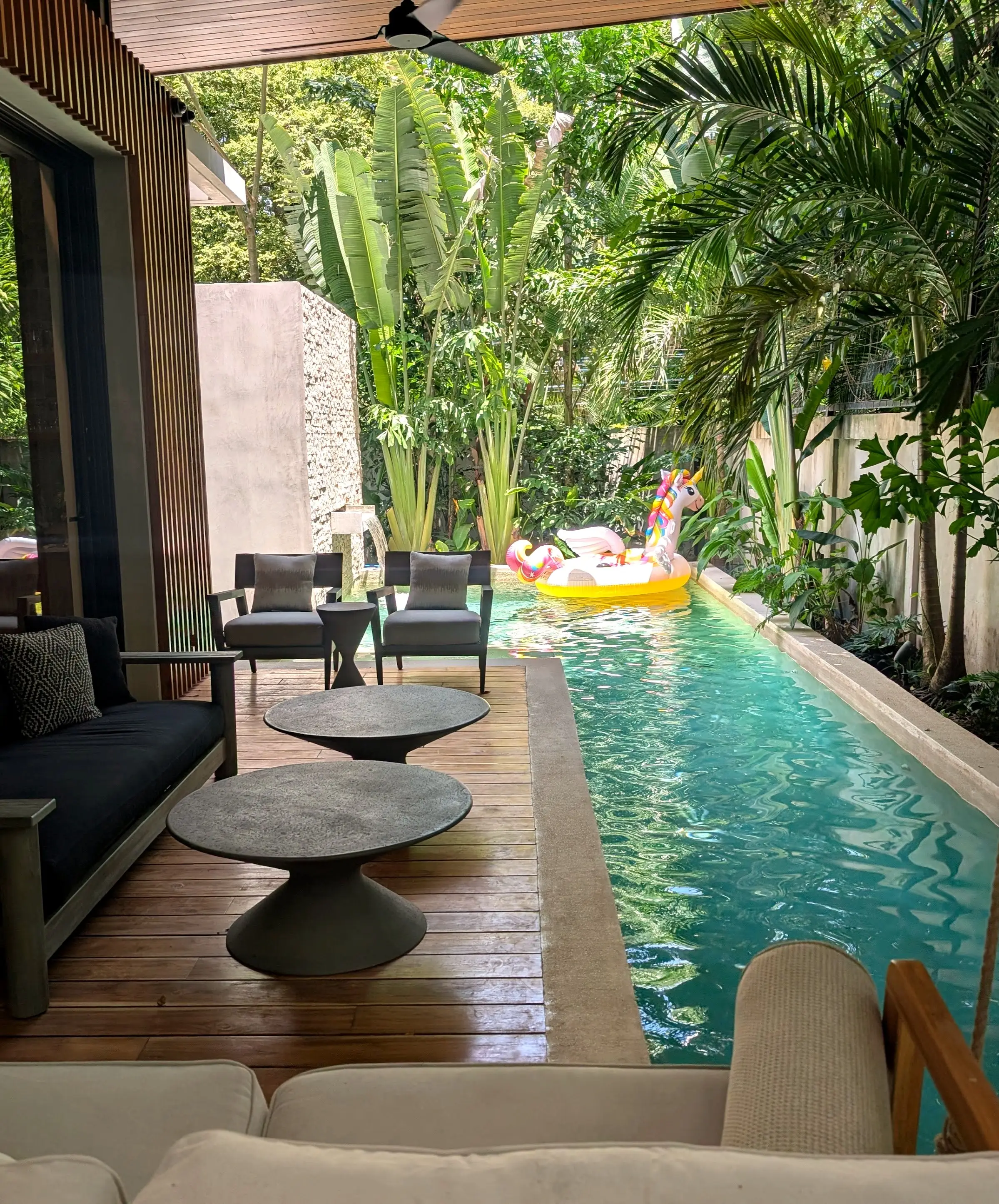 Kids' pool floats drifting down the lap pool, seen from the covered lounge