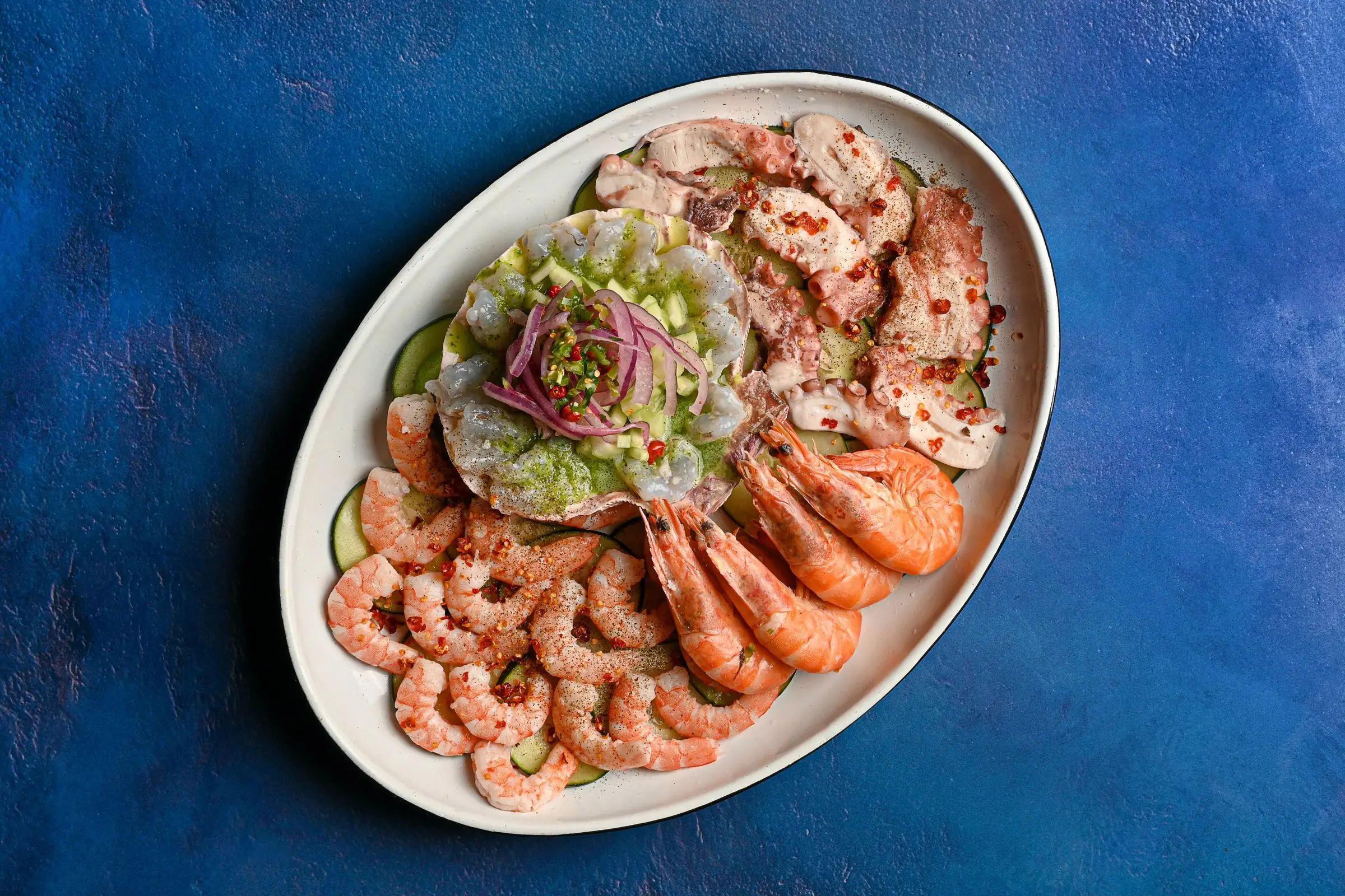 Fresh shrimp and octopus platter on a blue table